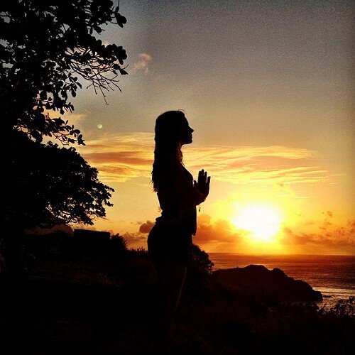Nascer do Sol Gayatri Mantra Mulher orando sentada ao nascer do Sol junto ao mar