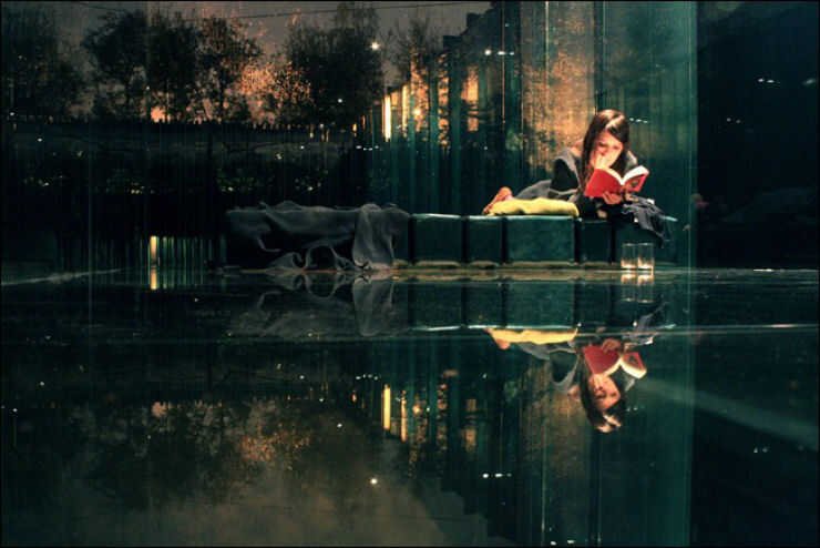 Reflexo de si não observado pela mulher leitora Mulher concentrada em sua leitura não observa seu belo reflexo. O mundo exterior reflete o ser interior.