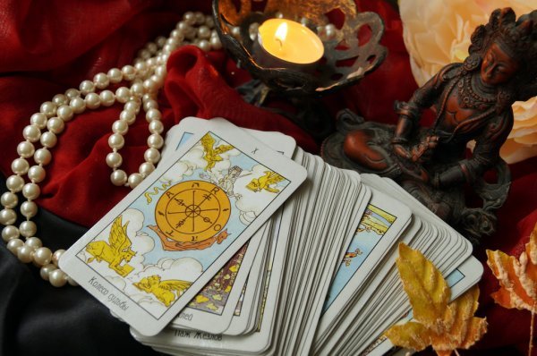 Mesa de Tarot e a Roda da Fortuna 10 Mesa de Tarot com a carta de Tarot A Roda da Fortuna 10 por cima das cartas, vela, colar de pérolas e Buda